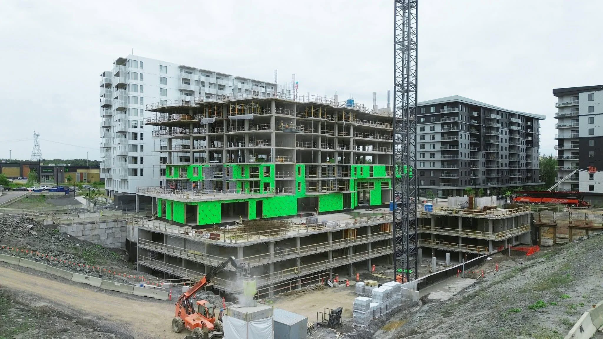Chantier d'immeubles à logements en construction, avec grue et étages en cours de fermeture